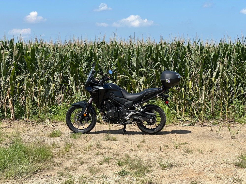 my motorcycle sitting in front of a field of corn